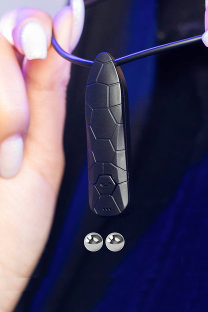 Close-up of Invisi2 Croco neck receiver held by hand, with two 2 mm bead earpieces shown below on dark background