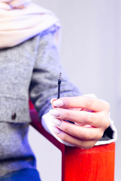 Woman holding slim black insertion tube with stacked 2 mm bead earpieces, focus on hand and tool.